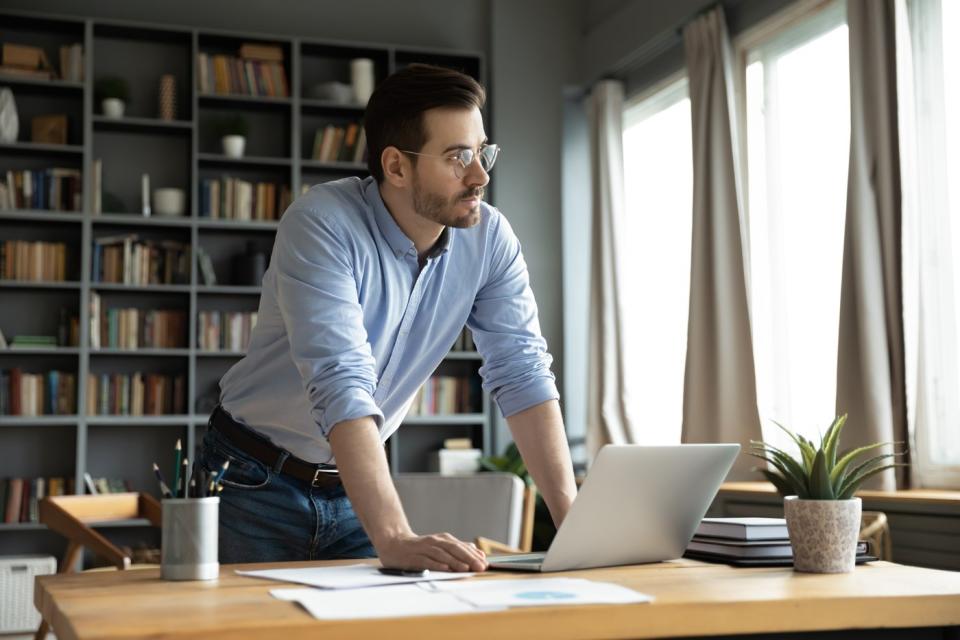 An investor in a home office looks pensively out the window.