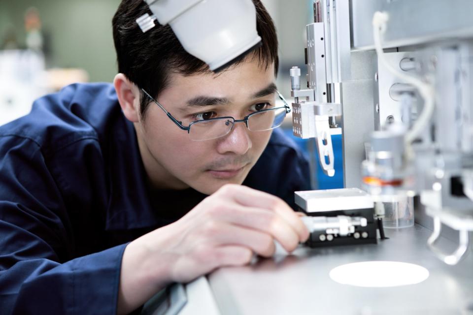 A semiconductor inspector closely examining manufacturing equipment.