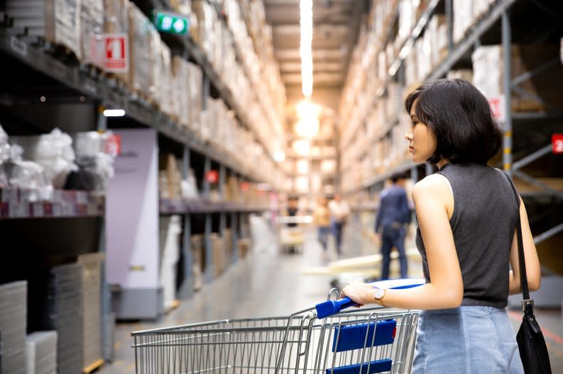 Warehouse club store shopper browsing aisle with shopping cart