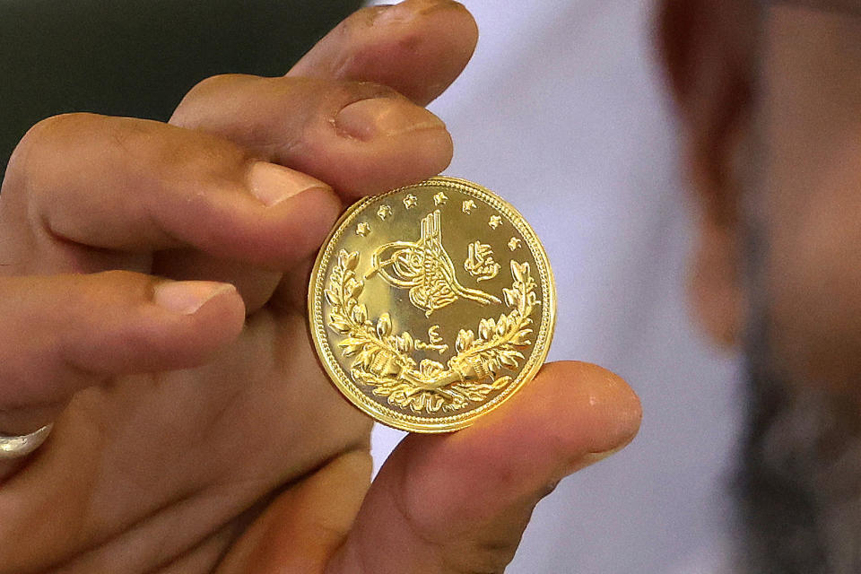 Kuwaiti gold maker and managing director of Dana solitaire company for formulation and trading of gold and jewellery Ameen Al-Qattan displays a coin at his shop in Kuwait City, on August 23, 2023. Gold prices have been fluctuating in Kuwait for the past few weeks. (Photo by YASSER AL-ZAYYAT / AFP) (Photo by YASSER AL-ZAYYAT/AFP via Getty Images)